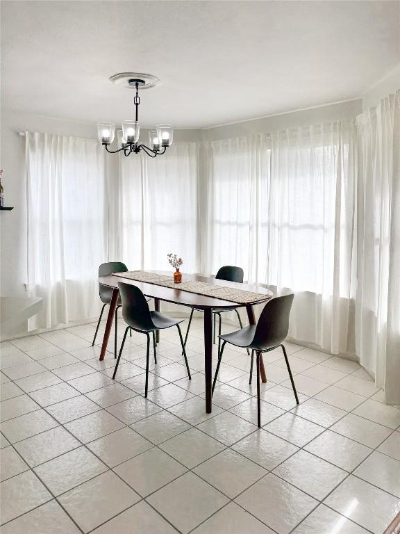 tiled dining space with an inviting chandelier and a healthy amount of sunlight