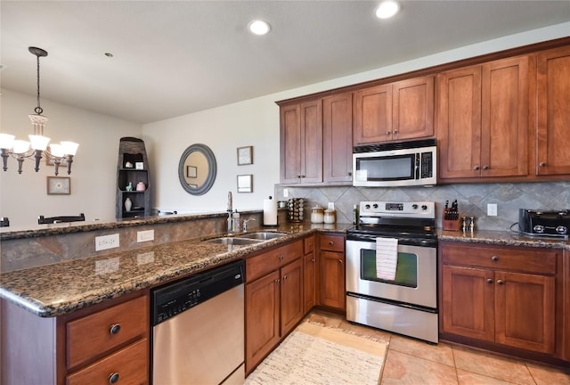 kitchen featuring pendant lighting, sink, dark stone countertops, appliances with stainless steel finishes, and kitchen peninsula