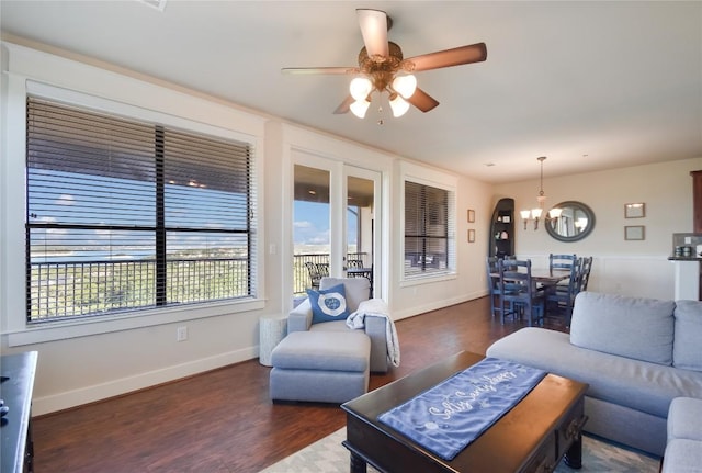 living room with ceiling fan with notable chandelier and dark wood-type flooring