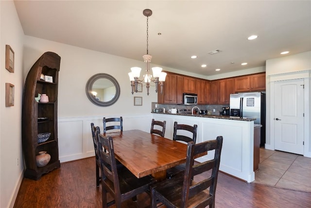 dining area with dark hardwood / wood-style floors, a notable chandelier, and sink