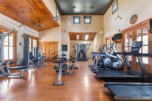 exercise room with wooden ceiling, french doors, hardwood / wood-style flooring, ceiling fan, and a towering ceiling