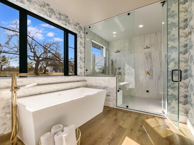 bathroom with wood-type flooring and shower with separate bathtub