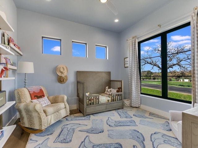 bedroom with a crib, multiple windows, and ceiling fan