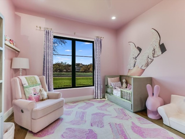 bedroom with hardwood / wood-style floors and a nursery area