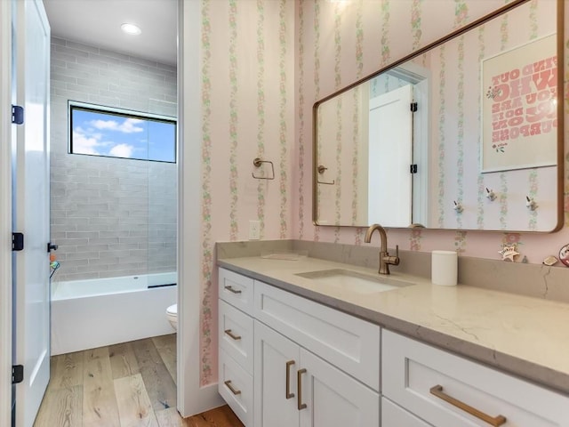 full bathroom with hardwood / wood-style floors, vanity, toilet, and tiled shower / bath combo