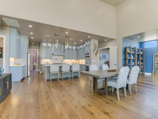 dining area with a high ceiling and light hardwood / wood-style flooring