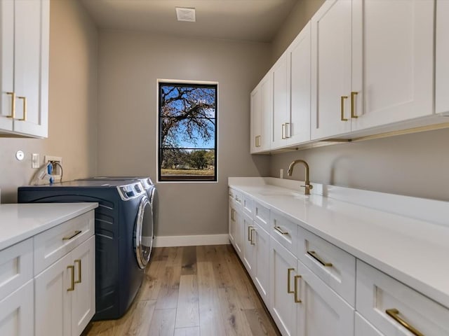 laundry room with cabinets, light hardwood / wood-style floors, washer and dryer, and sink