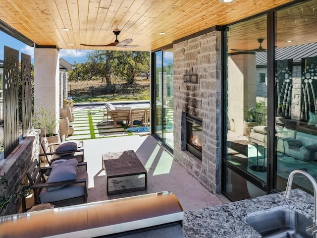 view of patio featuring ceiling fan, sink, and an outdoor stone fireplace