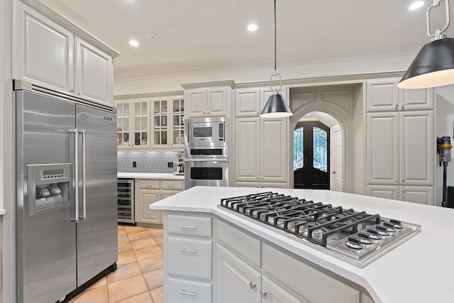 kitchen featuring white cabinetry, wine cooler, decorative light fixtures, and built in appliances