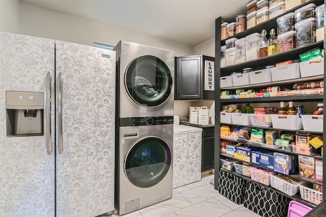 laundry area with cabinets and stacked washing maching and dryer