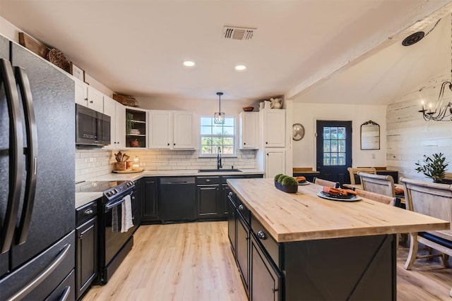 kitchen with a kitchen island, sink, black appliances, decorative light fixtures, and white cabinetry