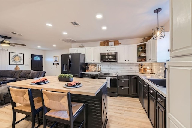 kitchen with white cabinetry, ceiling fan, stainless steel appliances, backsplash, and pendant lighting