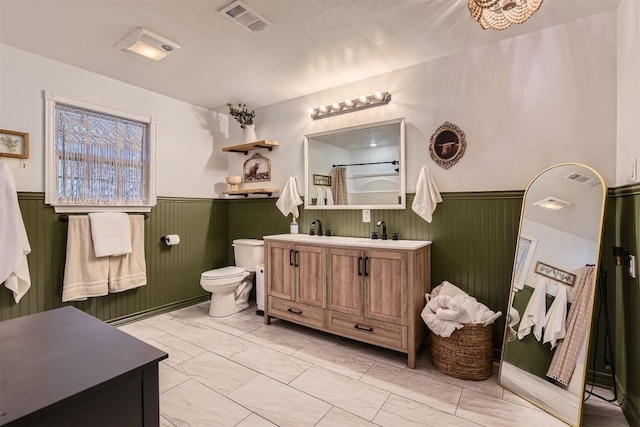 bathroom with vanity, toilet, and wooden walls