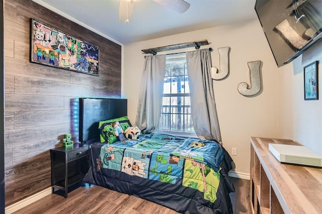 bedroom featuring ceiling fan, wood-type flooring, and wooden walls