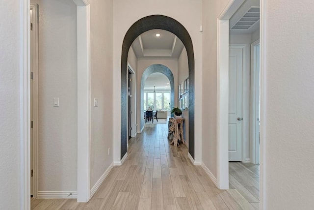 hall featuring a tray ceiling and light wood-type flooring