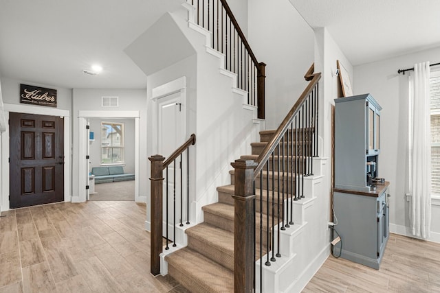 entrance foyer featuring stairs, baseboards, visible vents, and light wood-type flooring