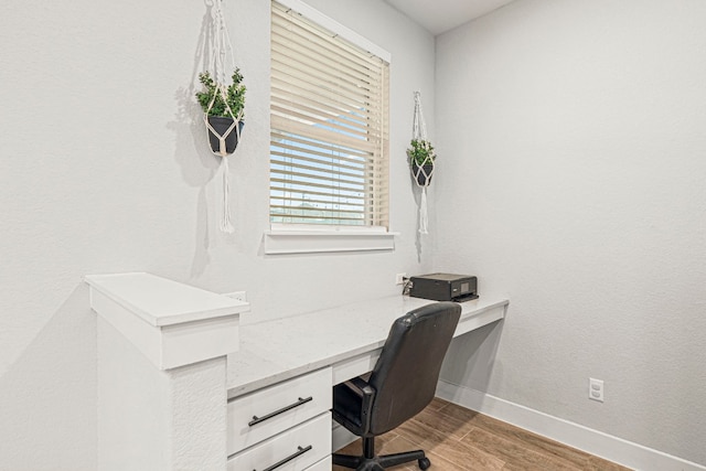 office with baseboards, wood finished floors, and built in study area