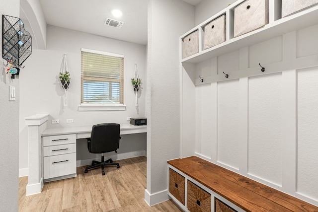 mudroom with light wood finished floors, visible vents, built in study area, and baseboards