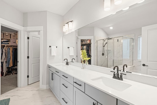 bathroom with double vanity, marble finish floor, a stall shower, and a sink