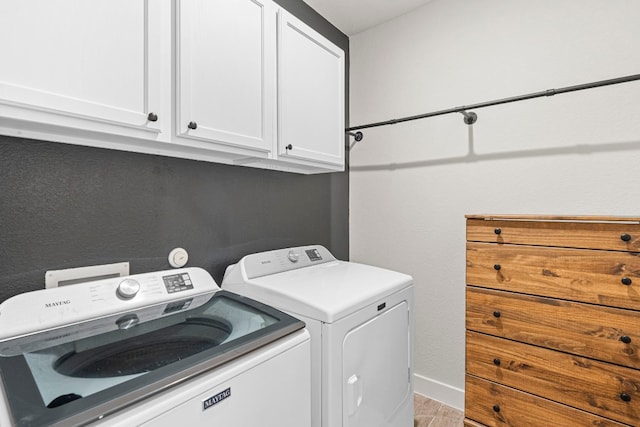 laundry room with cabinet space, baseboards, light wood-style floors, and separate washer and dryer