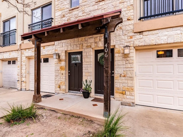 view of exterior entry with a balcony and a garage