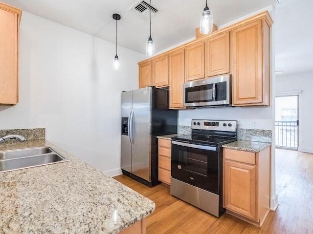 kitchen featuring decorative light fixtures, stainless steel appliances, light brown cabinetry, and sink