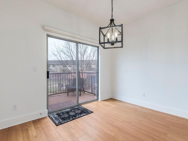 unfurnished dining area featuring wood-type flooring and an inviting chandelier