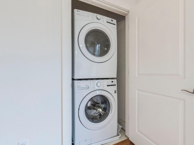 laundry room featuring hardwood / wood-style floors and stacked washer / drying machine