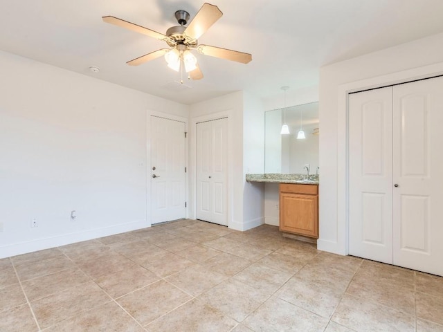 unfurnished bedroom with ceiling fan and multiple closets