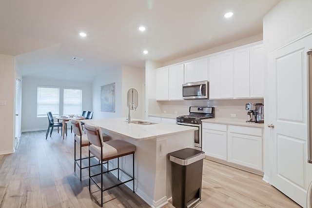 kitchen featuring white cabinetry, stainless steel appliances, sink, and an island with sink