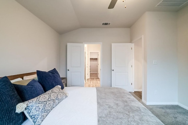 bedroom featuring ceiling fan, lofted ceiling, carpet, and a walk in closet