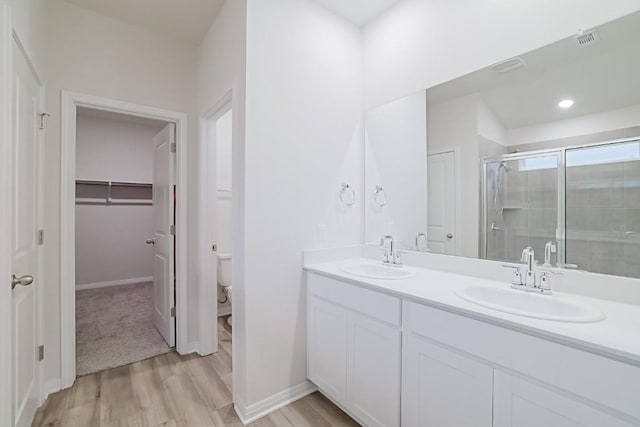 bathroom with a shower with door, wood-type flooring, vanity, and toilet