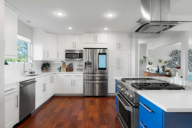 kitchen with appliances with stainless steel finishes, island range hood, sink, white cabinets, and blue cabinetry