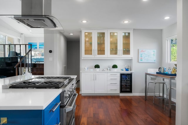 kitchen featuring stainless steel range with gas stovetop, wine cooler, island range hood, white cabinets, and dark hardwood / wood-style flooring