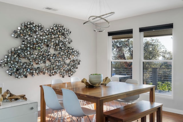 dining room featuring a notable chandelier, wood-type flooring, and a healthy amount of sunlight