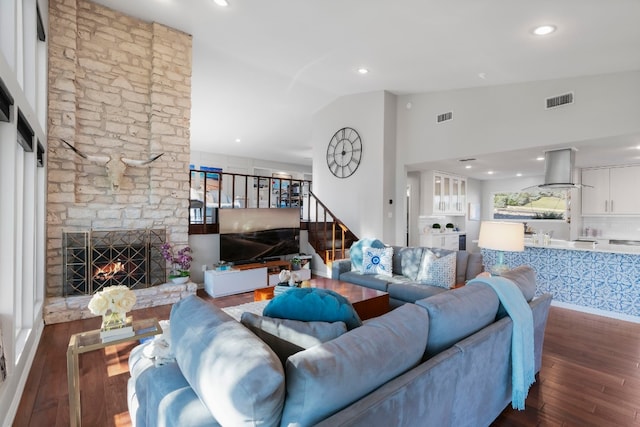 living room with a stone fireplace, high vaulted ceiling, and dark hardwood / wood-style floors