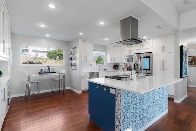 kitchen featuring dark wood-type flooring, a center island, appliances with stainless steel finishes, island exhaust hood, and white cabinets