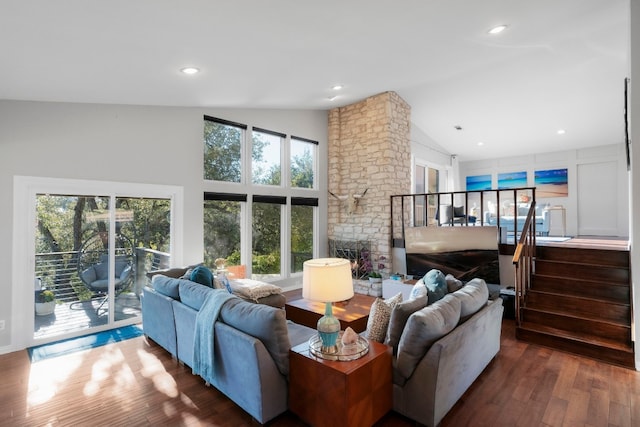 living room featuring wood-type flooring, a healthy amount of sunlight, a fireplace, and high vaulted ceiling