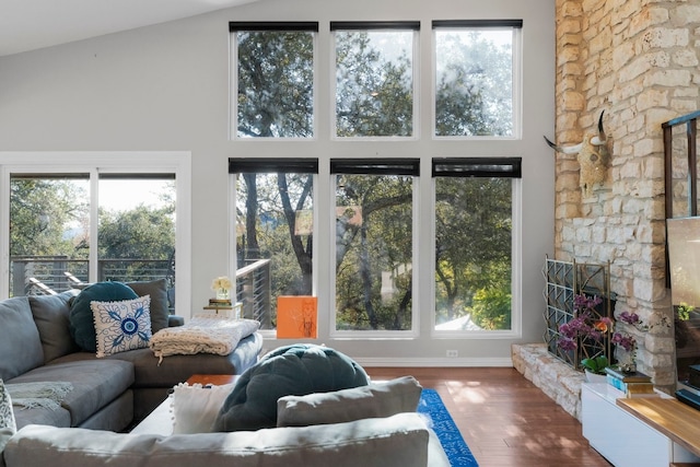 living room with a healthy amount of sunlight, hardwood / wood-style floors, and high vaulted ceiling