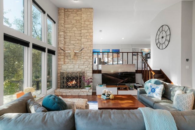 living room with lofted ceiling, hardwood / wood-style floors, and a stone fireplace