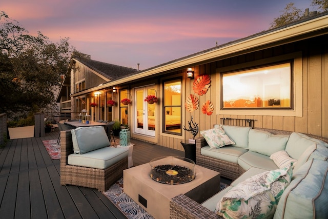 deck at dusk featuring an outdoor living space with a fire pit