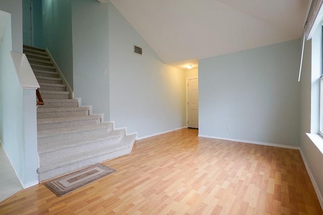 spare room featuring high vaulted ceiling and light hardwood / wood-style floors