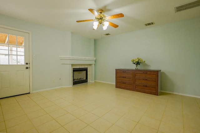 unfurnished living room featuring ceiling fan and a tiled fireplace