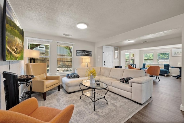 living room with a textured ceiling and light wood-type flooring