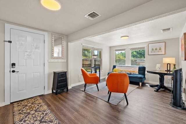 living area featuring visible vents, dark wood finished floors, a textured ceiling, and baseboards