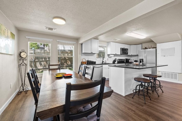 dining area with dark wood-type flooring, visible vents, and baseboards