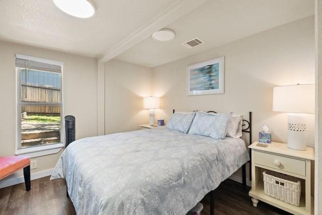 bedroom featuring baseboards, a textured ceiling, visible vents, and dark wood-style flooring