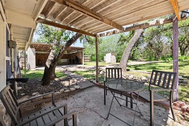 view of patio with a storage shed, outdoor dining space, and an outbuilding