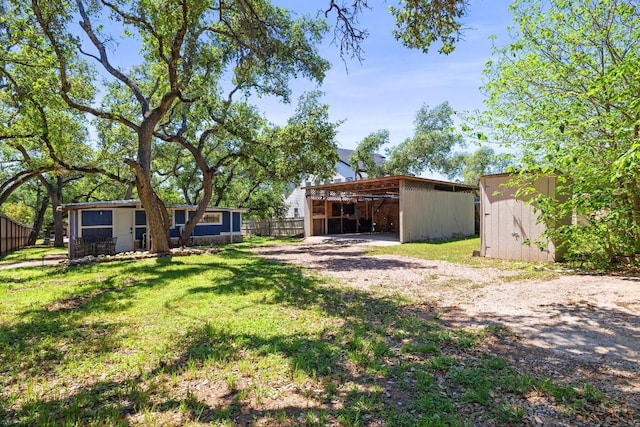 exterior space featuring driveway, fence, a pole building, and an outdoor structure