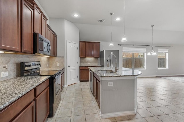 kitchen featuring light stone countertops, sink, decorative light fixtures, a kitchen island with sink, and appliances with stainless steel finishes